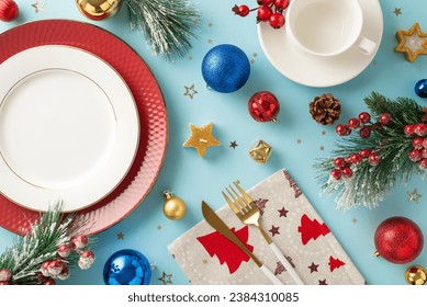 Curate Christmas table setup. Top-down view displaying ornate tableware, gleaming baubles, wintry twigs, holly berries, and festive elements against a pastel blue base for text or promotional content