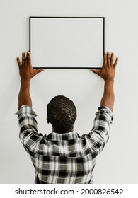 Curator hanging art frame mockup on the wall - Shutterstock ID 2000826542