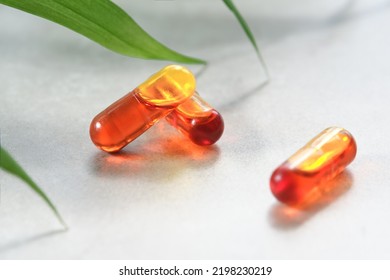 Curcumin In Liquid Form. Herbal Capsules, Herb Turmeric Capsules On Neutral Background With Palm Leaf Shadow. Herbal Medicine Extract From Turmeric Roots. Liquid Form Of Curcumin In Tiny Oil Micelles.