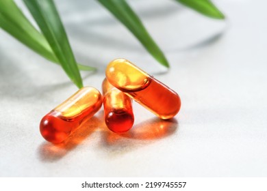 Curcumin In Liquid Form. Herbal Capsules, Herb Turmeric Capsules On Neutral Background With Palm Leaf Shadow. Herbal Medicine Extract From Turmeric Roots. Liquid Form Of Curcumin In Tiny Oil Micelles.