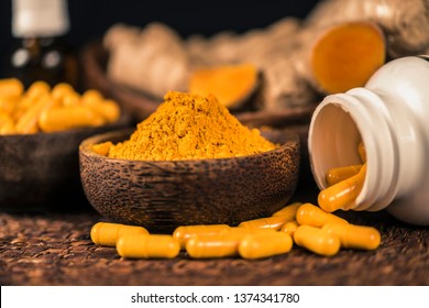 Curcumin supplement capsules, turmeric powder in glass bowl and curcuma root in background. Herbal medicine Curcuma against inflammation
