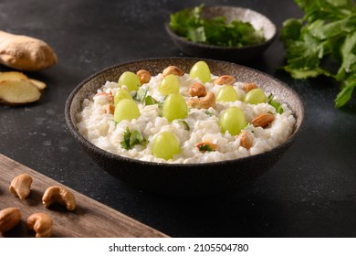 Curd Rice with cashews, grapes, cilantro, ginger on a dark background. Indian South cuisine. Close up.
