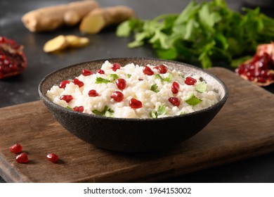 Curd Rice with pomegranate, cilantro, mustard seeds, ginger on a dark background. Indian South cuisine. Close up.