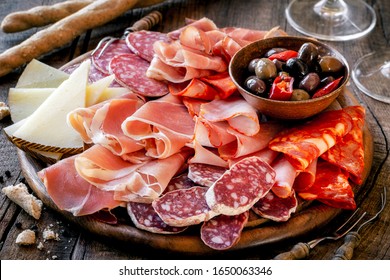 Cured Meat Platter With Cheese And Spicy Olives Served As Traditional Spanish Tapas On A Wooden Board. Selection Of Ham, Salami And Goat Cheese