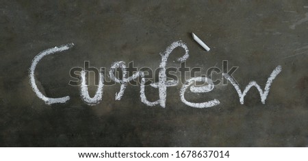 CURFEW Word Written with White Chalk on Black Background