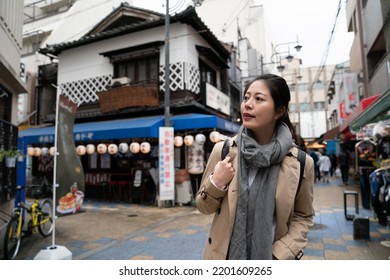 Curious Asian Japanese Female Tourist Enjoying Looking Around At Paved Food District While Exploring In Shinsekai Area In Osaka Japan At Spring Time