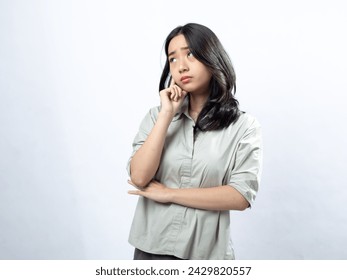 Curious Asian woman with hand on chin, gazing away, wearing a muted blouse, against a white background - Powered by Shutterstock