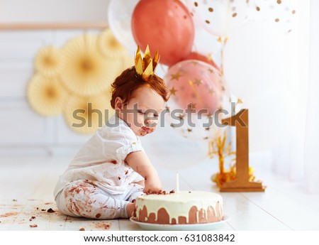 curious baby boy poking finger in his first birthday cake