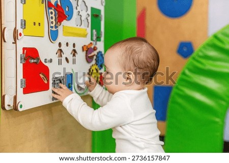 Curious baby exploring an interactive activity board at daycare, developing fine motor skills, sensory learning, and early childhood cognitive abilities.