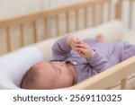 Curious baby lying in crib looking at his hand