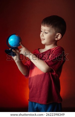 Curious boy exploring a small globe. Dreaming of world travel and childhood adventures.