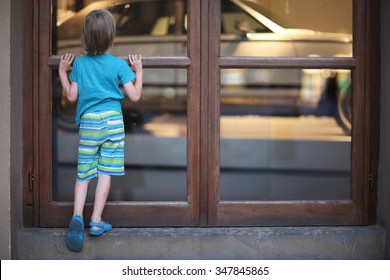 Curious boy looking at car behind closed doors