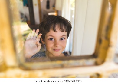 A Curious Boy Looks Out The Window, Portrait Of A Boy, Observation Through The Window, The Emotions Of A Child, Kid Looks Out Of The Window Of A House, Quarantine Self-isolation, Boy Waving.