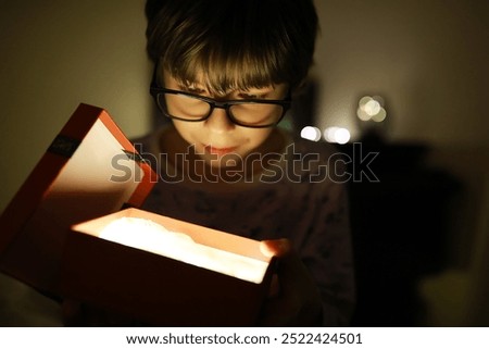 Curious Boy Opening Glowing Gift Box in Dim Light