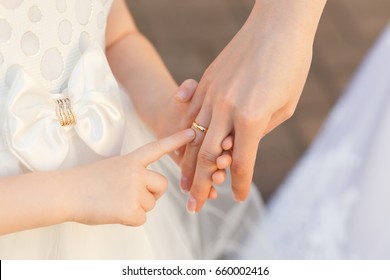 The Curious Child Touches The Engagement Ring On The Finger Of The Bride