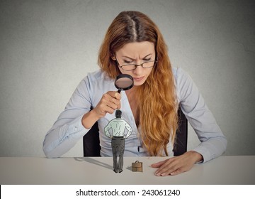 Curious Corporate Businesswoman Skeptically Meeting Looking At Small Employee Standing On Table Through Magnifying Glass Isolated Grey Office Wall Background. Human Face Expression Attitude Perception