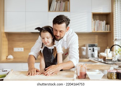 Curious Daughter Child Kid Cooking With Father Kneading Rolling Dough With Hands For Baking Cooking Homemade Pizza In Modern Kitchen At Home.