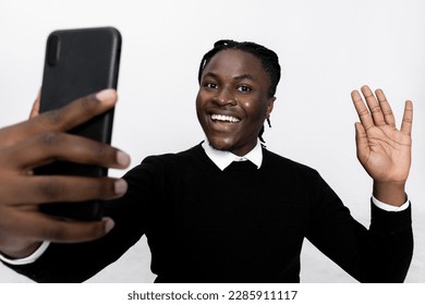 Curious delighted handsome boy with beautiful white teeth smiling looking at camera waving holding cellphone in hands having video conference chat with friends family. - Powered by Shutterstock