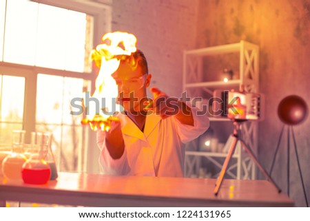 Curious experimenter. Curious experimenter causing fire on his palm wearing special protective clear glasses