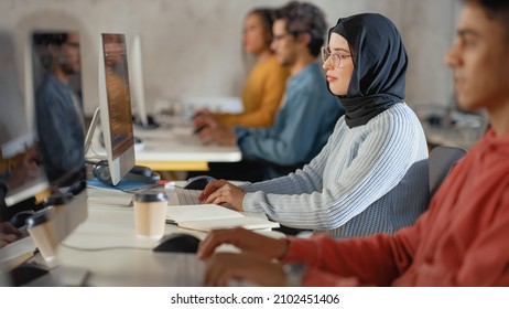 Curious Female Muslim Student Wearing A Hijab, Studying In Modern University With Diverse Multiethnic Classmates. College Scholars Work In College Room, Learning IT, Programming Or Computer Science.