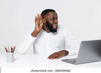 Curious Fun Young African American Business Man In Classic Shirt Posing Work In Office Sit At Desk With Laptop Pc Try To Hear You Overhear Listening Intently Isolated On White Color Background Studio.