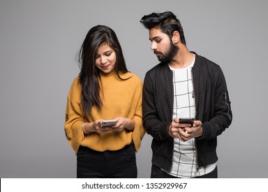 Curious indian boyfriend is spying his lovers smartphone standing on gray background - Shutterstock ID 1352929967