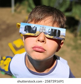 Curious kid watching a solar eclipse wearing special protective sunglasses.