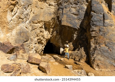 Curious little boy exploring a cave entrance with a stick on a sunny day. Concept of childhood adventure, outdoor exploration, and natural discovery. High quality photo - Powered by Shutterstock