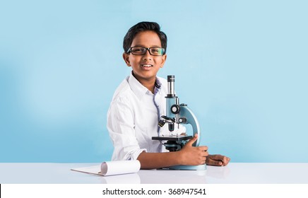 Curious little Indian asian school kid or scientist studying science, experimenting with chemicals or microscope at laboratory, selective focus - Powered by Shutterstock