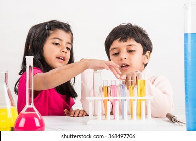 Curious little Indian school kids or scientists studying science, experimenting with chemicals or microscope at laboratory, selective focus