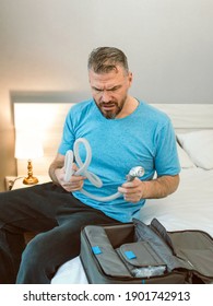 curious man with chronic breathing issues surprised by using  CPAP machine sitting on the bed in bedroom. Healthcare, CPAP, Obstructive sleep apnea therapy, snoring concept