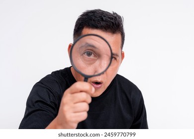 A curious middle-aged Asian man uses a magnifying glass to closely inspect or observe, isolated on a white background. - Powered by Shutterstock