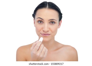 Curious natural model using lip balm on white background