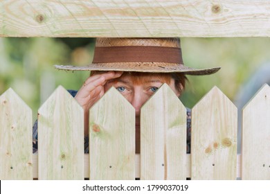 Curious neighbor stands behind a fence and watches