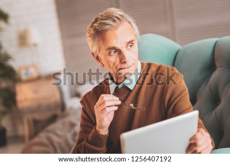 Curious news. Aged retired man feeling rather thoughtful after reading curious news in financial magazine