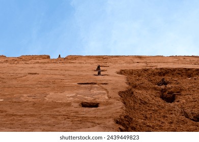 Curious pigeons peeks through ancient wall's crevices, under Marrakech's vast, cloud-speckled azure expanse. - Powered by Shutterstock