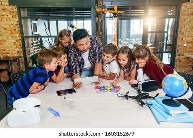 Curious Pupils Watching Attentively Their Korean Male Teacher Use Device Of Tablet Computer To Explain Electronic Basic Principles At School.