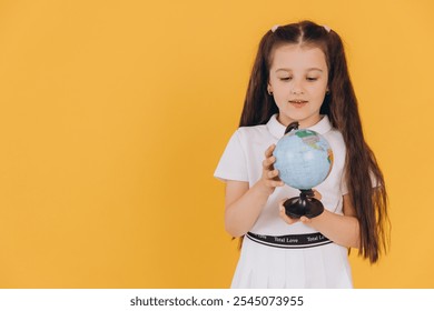 Curious schoolgirl holding a globe, learning about world geography and different countries, against a vibrant yellow backdrop - Powered by Shutterstock