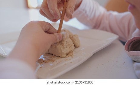 Curious Smart Intelligent Young Caucasian Girl Playing With Creative Archeology Education Kit Toy Trying To Dig Out Fossil Bones Of Dinosaur From Sandstone Brick Using Brush And Wooden Chisel