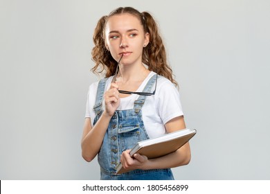 Curious Student Portrait. High School Education. Thoughtful Smart Teen Girl With Books Eyeglasses Isolated On Light Empty Space Background. College Library. Knowledge Information.