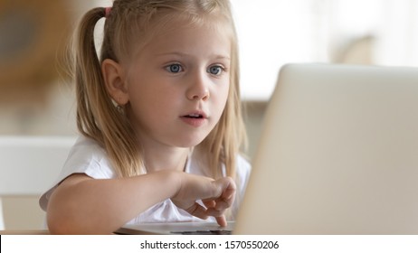 Curious Surprised Cute Little Kid Girl Using Laptop Alone At Home, Smart Excited Preschool Child Learning Computer Internet Without Parental Control At Home, Children Education Tech Addiction Concept