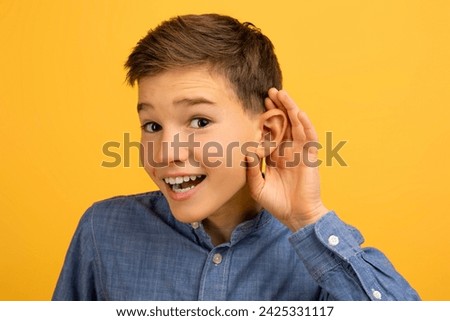 Curious Teen Boy Holding Hand Near Ear Trying To Overhear Something, Excited Teenage Male Kid Interested In Fresh Gossips, Standing Isolated On Yellow Studio Background, Closeup Shot