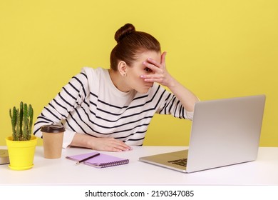 Curious Woman Manager Sitting At Workplace, Spying, Looking Through Fingers At Laptop Screen, Peeking Secret Gossip In Office. Indoor Studio Studio Shot Isolated On Yellow Background.