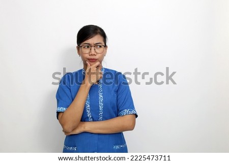 Curious young asian woman standing while glancing sideways. Isolated on white with copyspace