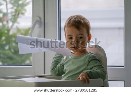 Curious young child exploring imagination and creative play with a paper craft. Early childhood development and learning through play concept.