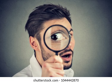 Curious young man looking through a magnifying glass 