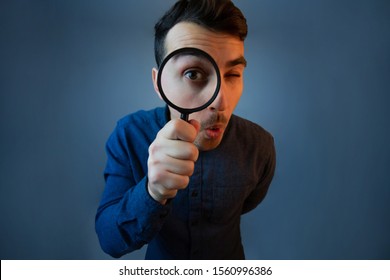 Curious young man with magnifying glass Isolated on grey background. Surprised Young man student holding magnifying glass. - Shutterstock ID 1560996386