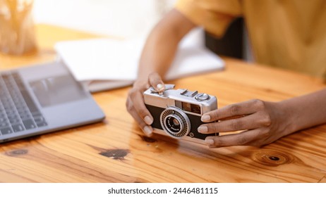 Curious young woman exploring a vintage film camera at a well-lit indoor workspace with technology around. - Powered by Shutterstock