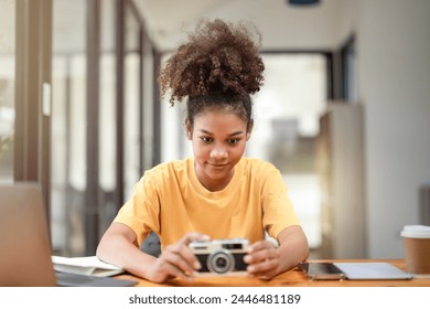 Curious young woman exploring a vintage film camera at a well-lit indoor workspace with technology around.
 - Powered by Shutterstock