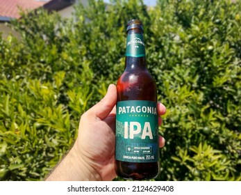 Curitiba, Brazil - February 13, 2022 Holding In Hand A Bottle Of Patagonia Beer, Greenery Or Garden Background. 355ml Ipa Beer, Pure Malt Beer. 